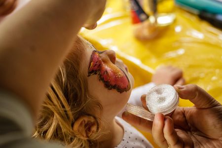 Sitzendes Kind beim Kinderschminken.