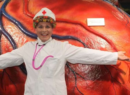 Comedian Lilli als Krankenschwerster verkleidet vor einem übergroßen Herzen.