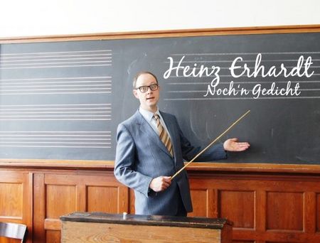 Mann in Anzug mit Brille präsentiert vor einer Tafel mit der Aufschrift "Heinz Erhardt - Noch 'n Gedicht".