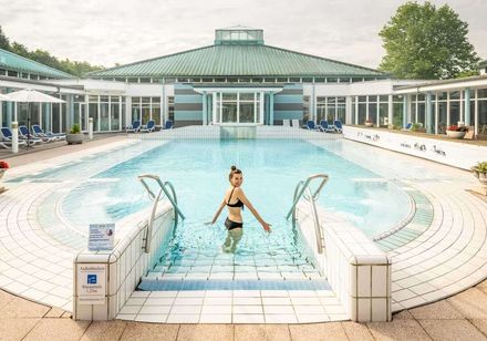 Eine Frau badet entspannt im Außenbecken der Driburg Therme.