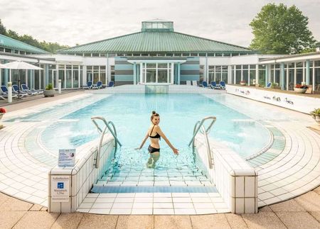 Eine Frau badet entspannt im Außenbecken der Driburg Therme.